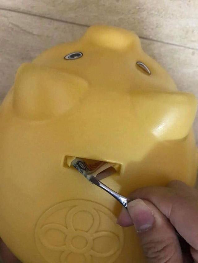 Một chú heo đất màu xanh với vết rạch khéo léo ở bụng, cho thấy cách móc tiền mà không cần phá hủy hoàn toàn.
